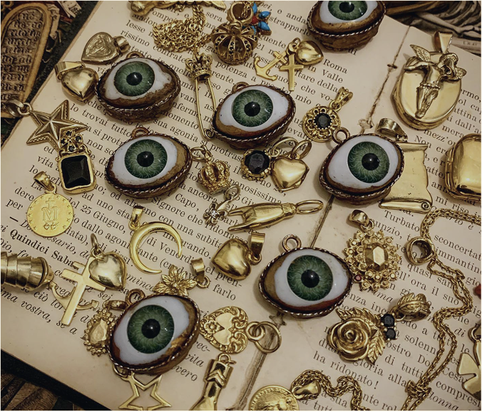 Marco De Luca jewelry pieces — handcrafted charms and pendants on antique manuscript